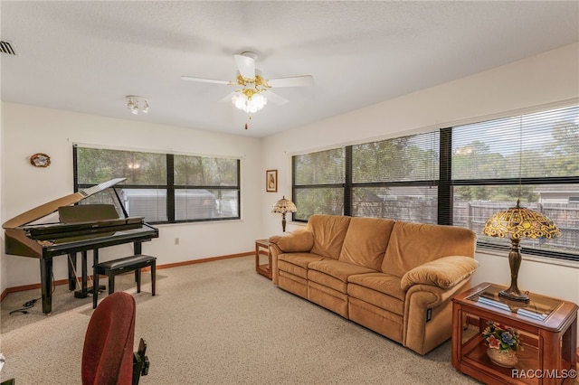 carpeted living area featuring a ceiling fan, visible vents, and baseboards