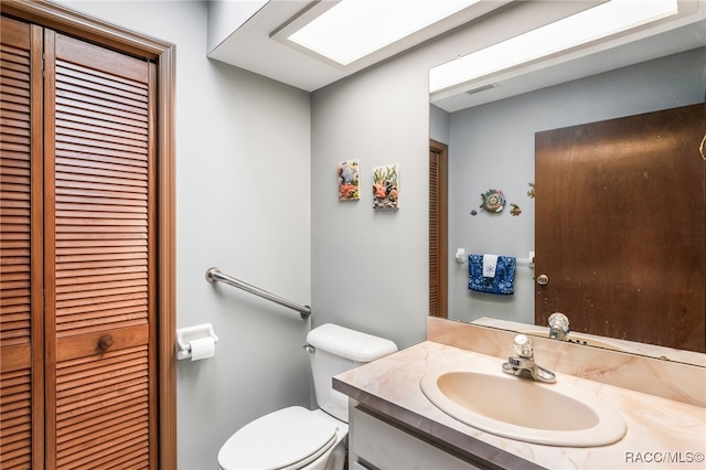 half bath featuring visible vents, toilet, a skylight, a closet, and vanity