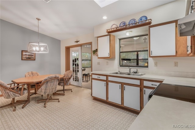 kitchen featuring a healthy amount of sunlight, a sink, hanging light fixtures, light countertops, and extractor fan