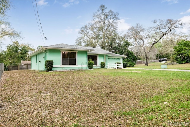 view of front of home featuring stucco siding, a front lawn, an attached garage, and fence