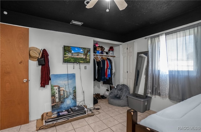 tiled bedroom with ceiling fan and a closet