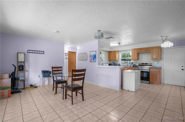 kitchen with kitchen peninsula, light tile patterned floors, a textured ceiling, and stainless steel electric stove