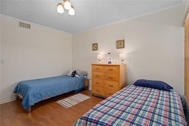 bedroom with hardwood / wood-style floors, ornamental molding, and a textured ceiling