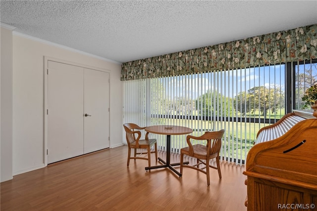 dining area featuring hardwood / wood-style flooring, ornamental molding, and a textured ceiling