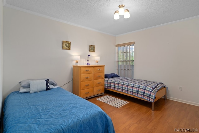 bedroom with hardwood / wood-style floors, ornamental molding, and a textured ceiling