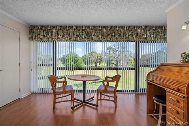 dining room with wood-type flooring, ornamental molding, and a textured ceiling