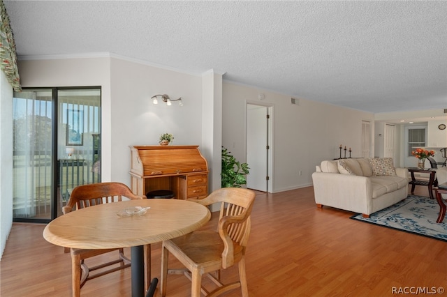 dining area featuring crown molding, a textured ceiling, and light hardwood / wood-style flooring