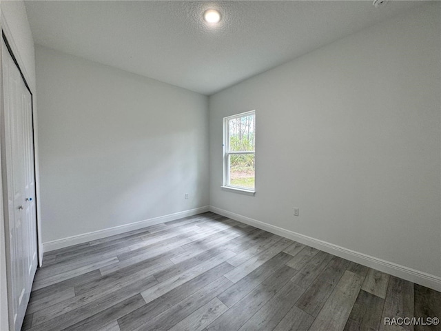 7549 N Santos Dr, Citrus Springs, FL 34434 - unfurnished bedroom featuring wood finished floors, baseboards, a closet, and a textured ceiling
