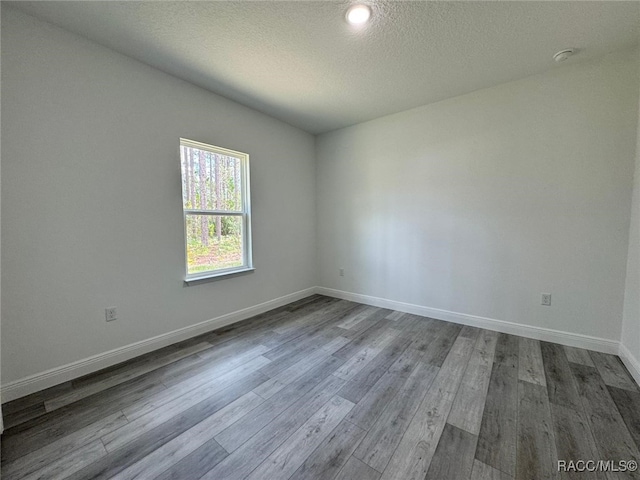 7549 N Santos Dr, Citrus Springs, FL 34434 - spare room featuring dark wood-type flooring, baseboards, a textured ceiling, and a smoke detector