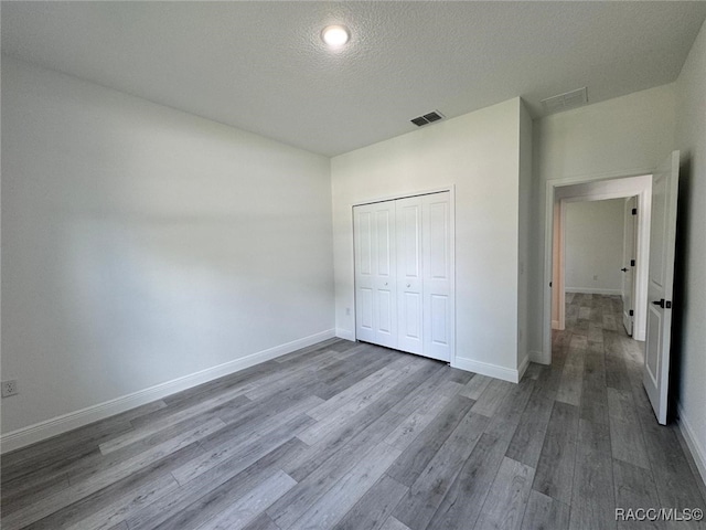 7549 N Santos Dr, Citrus Springs, FL 34434 - unfurnished bedroom featuring wood finished floors, baseboards, a closet, and a textured ceiling