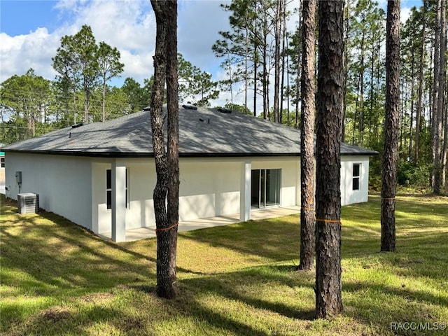 7549 N Santos Dr, Citrus Springs, FL 34434 - view of side of property with stucco siding, a yard, central AC, and roof with shingles