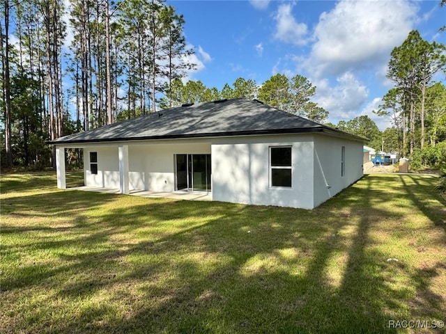 7549 N Santos Dr, Citrus Springs, FL 34434 - rear view of house featuring stucco siding, a yard, and roof with shingles