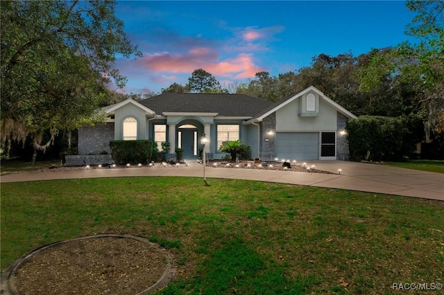 ranch-style home featuring concrete driveway, a yard, an attached garage, and stucco siding