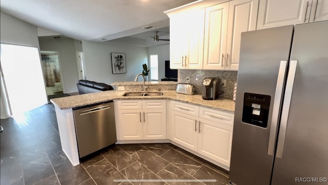 kitchen with white cabinets, kitchen peninsula, sink, and appliances with stainless steel finishes