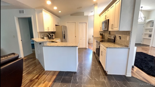 kitchen featuring lofted ceiling, dark wood-type flooring, white cabinetry, kitchen peninsula, and stainless steel appliances