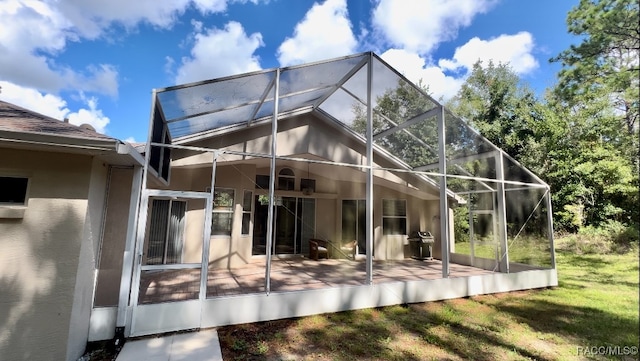 back of property with glass enclosure and a patio area