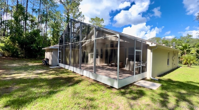 back of house featuring a lawn, glass enclosure, and a patio area