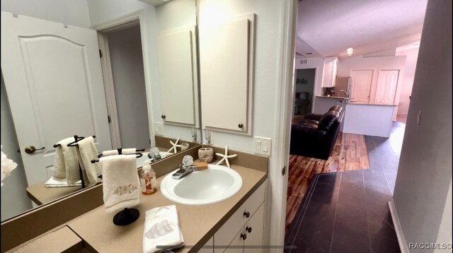 bathroom with vanity, hardwood / wood-style flooring, and vaulted ceiling