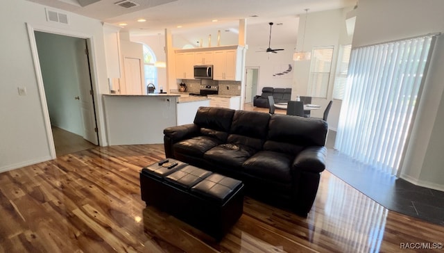 living room featuring a towering ceiling, dark hardwood / wood-style flooring, and ceiling fan