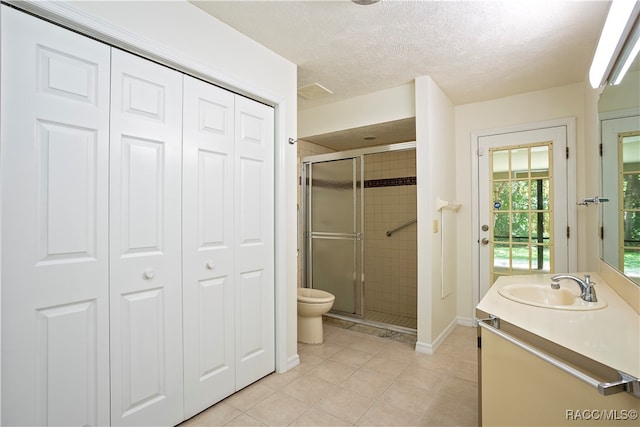 bathroom with tile patterned floors, vanity, toilet, and a shower with door