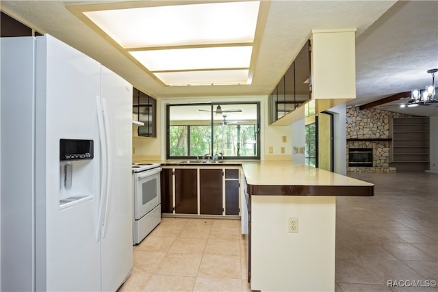 kitchen with sink, kitchen peninsula, a textured ceiling, white appliances, and a fireplace