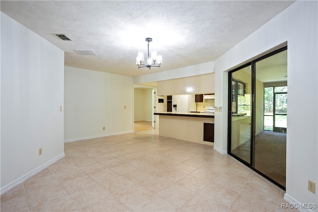 tiled empty room with a notable chandelier and a textured ceiling