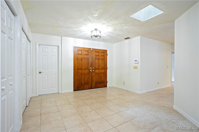 foyer featuring a skylight, light tile patterned floors, and a textured ceiling