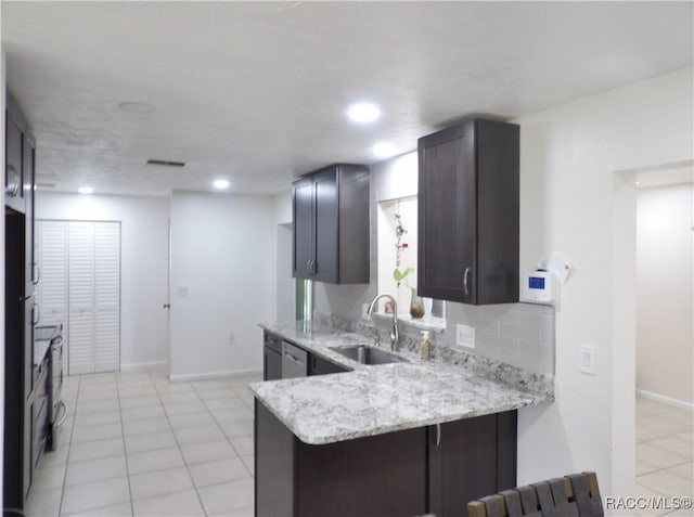 kitchen featuring kitchen peninsula, decorative backsplash, light stone countertops, sink, and light tile patterned floors