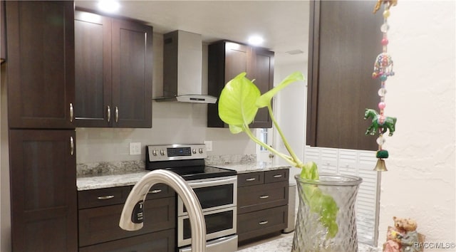 kitchen featuring tasteful backsplash, light stone countertops, double oven range, and wall chimney range hood