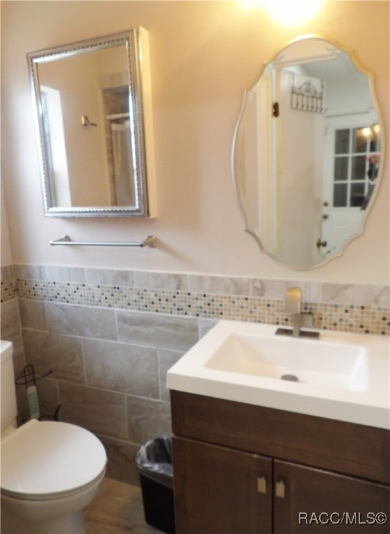 bathroom featuring vanity, toilet, and tile walls