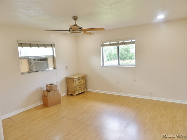 spare room with light hardwood / wood-style flooring, cooling unit, and ceiling fan