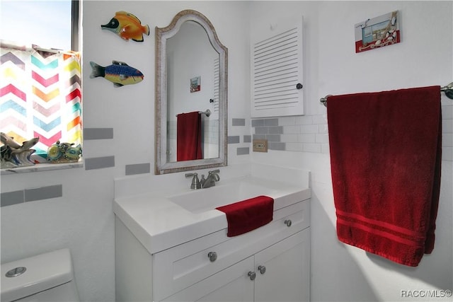 bathroom with decorative backsplash, vanity, and toilet