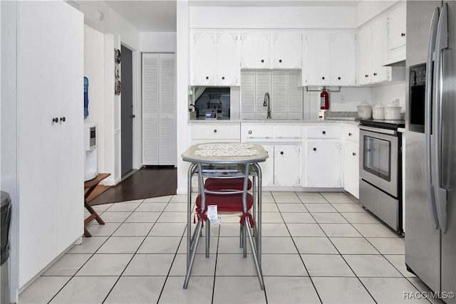 kitchen featuring appliances with stainless steel finishes, light tile patterned floors, white cabinetry, and sink