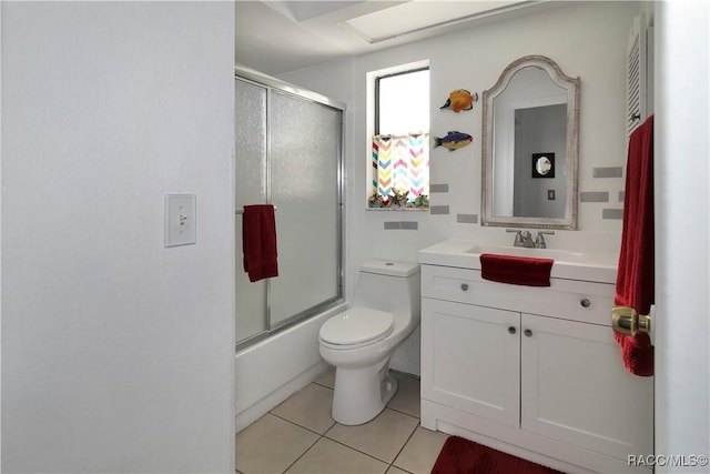 full bathroom with tile patterned flooring, vanity, bath / shower combo with glass door, and toilet