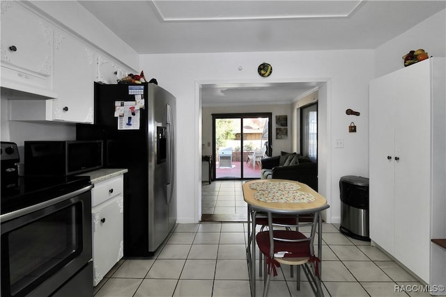 kitchen featuring white cabinets, light tile patterned flooring, stainless steel fridge with ice dispenser, and black range with electric cooktop