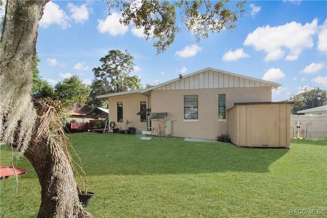 rear view of property featuring a lawn and a storage shed