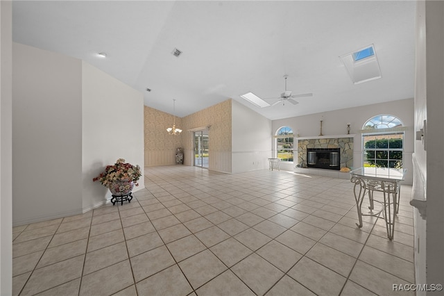 unfurnished living room with ceiling fan with notable chandelier, light tile patterned floors, a fireplace, and lofted ceiling