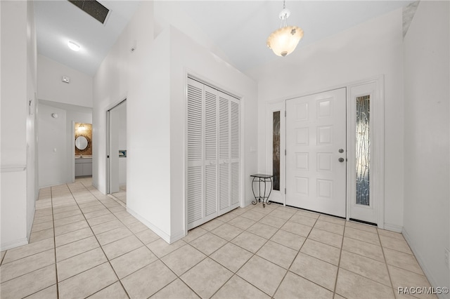 entryway featuring light tile patterned flooring and high vaulted ceiling