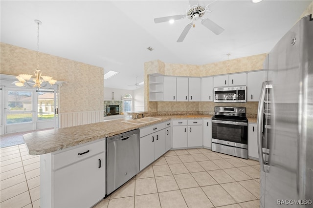 kitchen with sink, kitchen peninsula, white cabinets, ceiling fan with notable chandelier, and appliances with stainless steel finishes