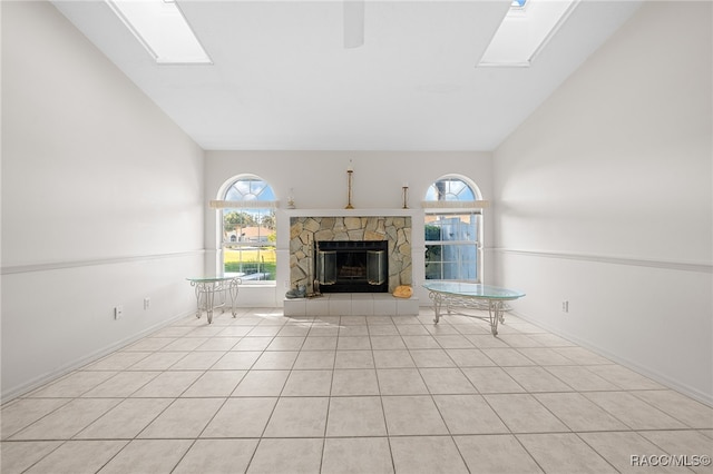 unfurnished living room featuring a fireplace, light tile patterned floors, and lofted ceiling with skylight