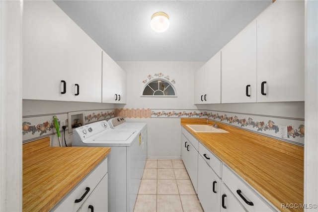 washroom featuring cabinets, a textured ceiling, sink, light tile patterned floors, and washing machine and dryer