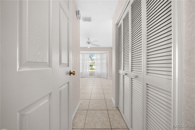 hall featuring light tile patterned floors and a textured ceiling