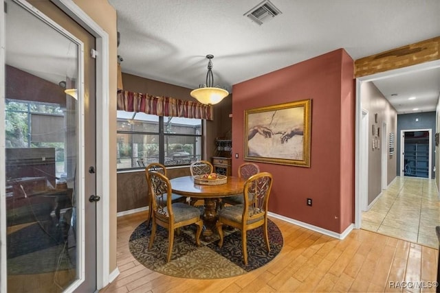 dining area with visible vents, baseboards, and light wood-style flooring