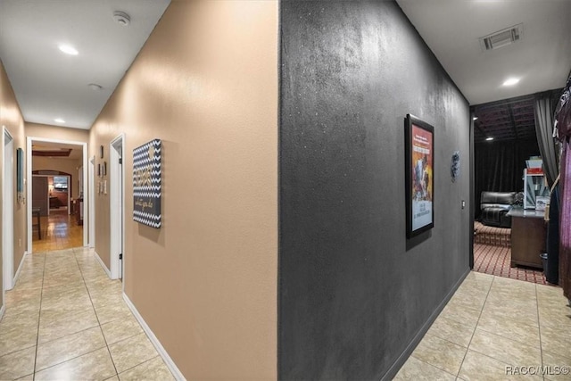 corridor featuring visible vents, baseboards, light tile patterned flooring, recessed lighting, and arched walkways