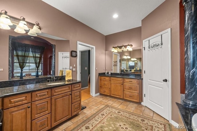 full bath with a sink, baseboards, and two vanities