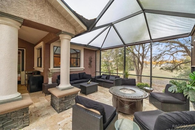 view of patio / terrace featuring an outdoor living space with a fire pit and glass enclosure