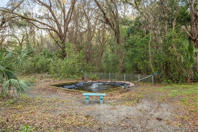 view of yard with a wooded view and fence