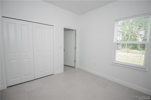 unfurnished bedroom with a closet, multiple windows, and light tile patterned flooring