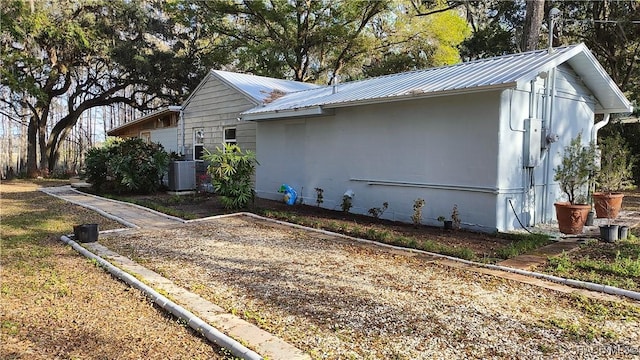 view of property exterior with central AC and metal roof