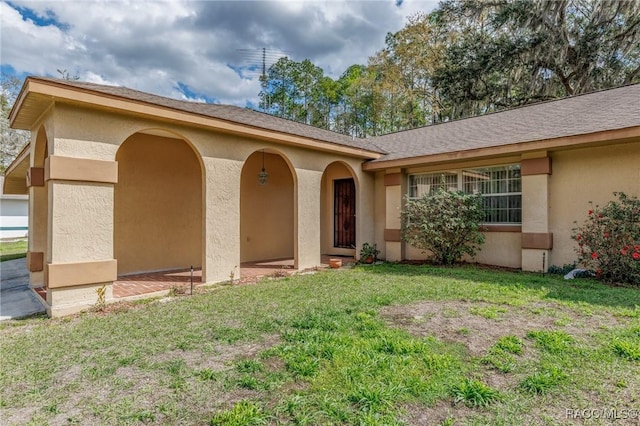 entrance to property featuring a lawn and stucco siding